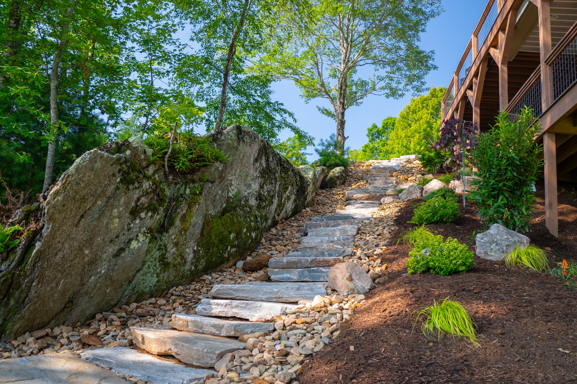 Sweeping flagstone staircase bordered by river rock and plantings